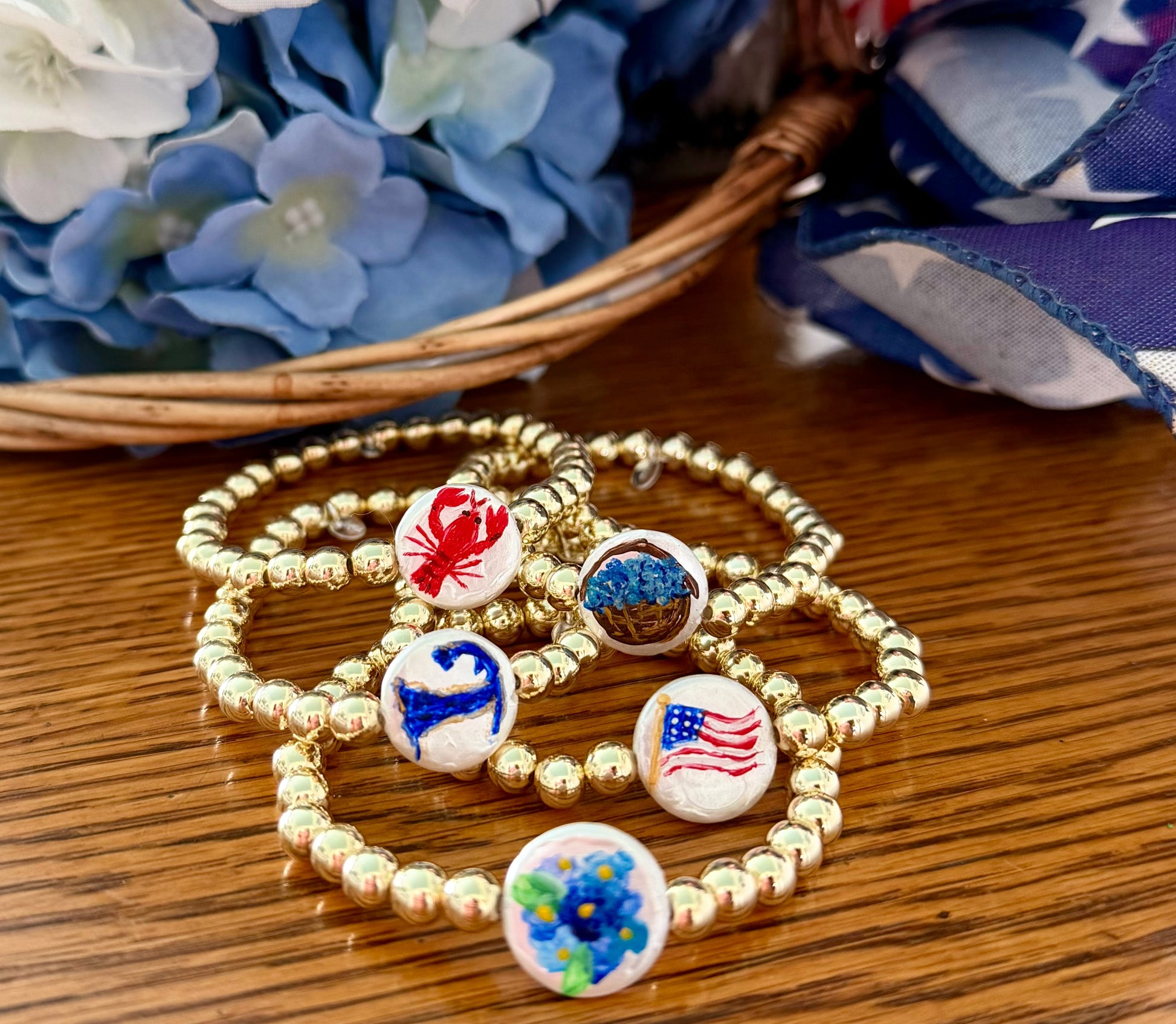 Gold beaded bracelet with colorful bead charms on a wooden surface with flowers in the background
